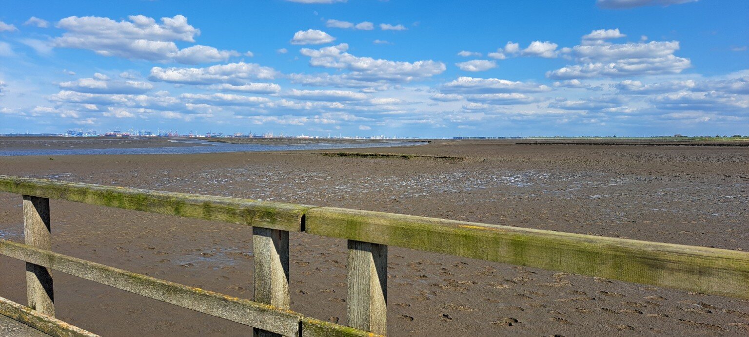 Wattenmeer in Butjadingen mit Hafenkränen am Horizont
