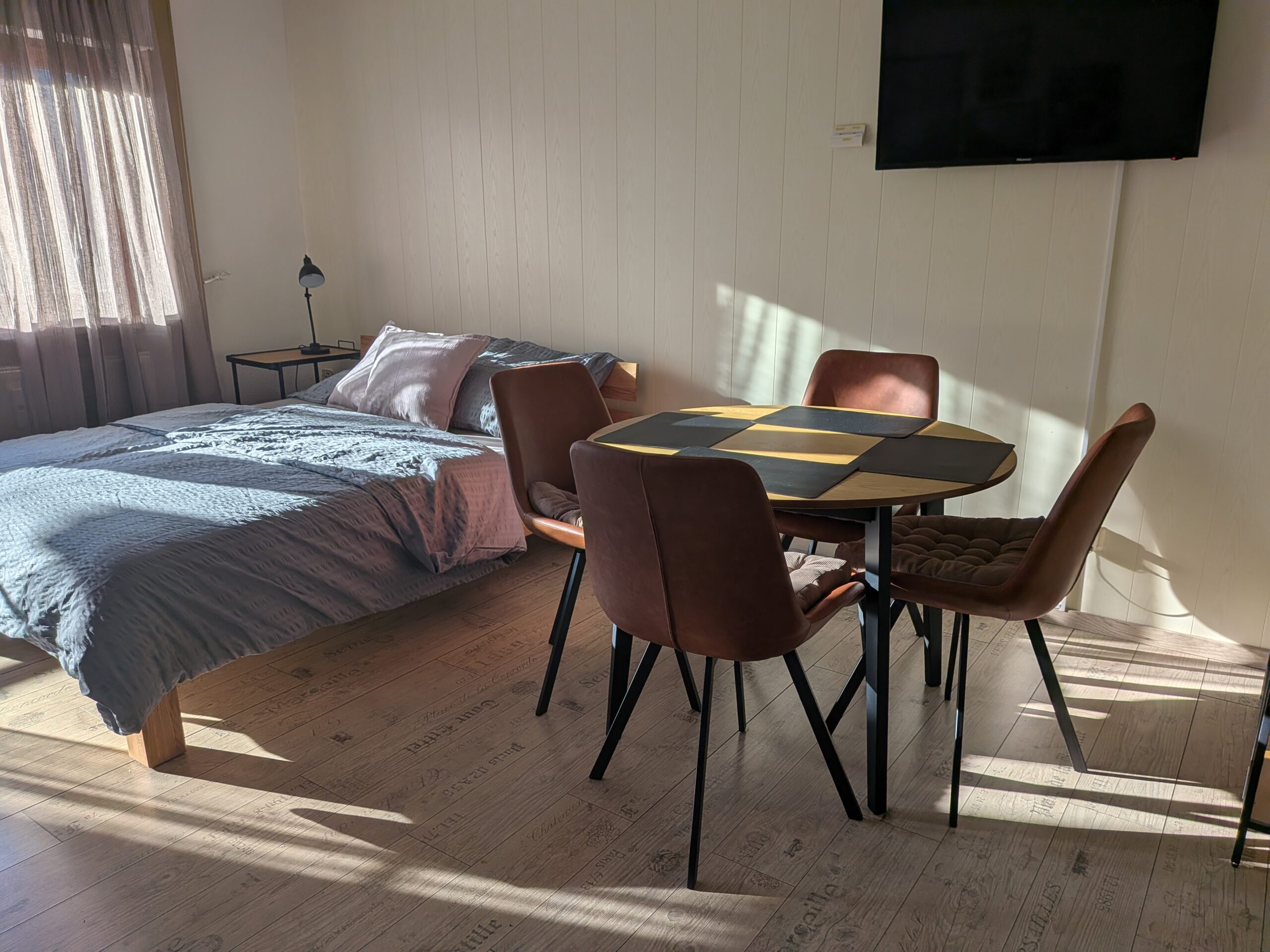 Wohn- und Schlafbereich mit Doppelbett und Esstisch