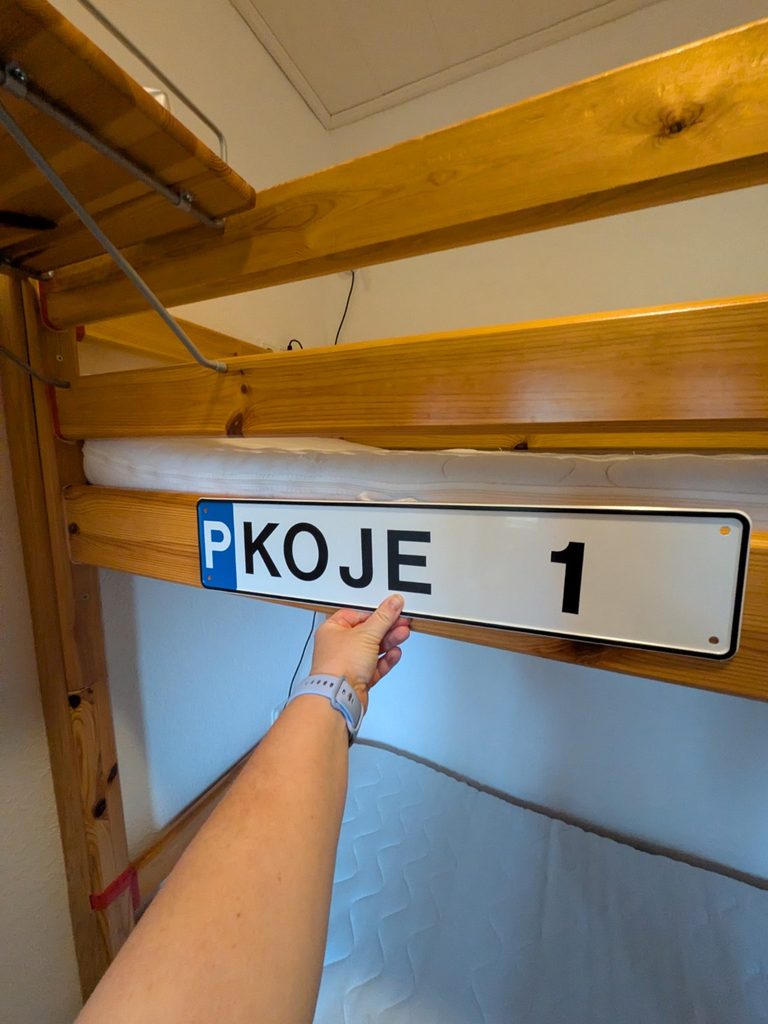 Anbringen des Parkplatzschildes KOJE 1 am hölzernen Etagenbett
